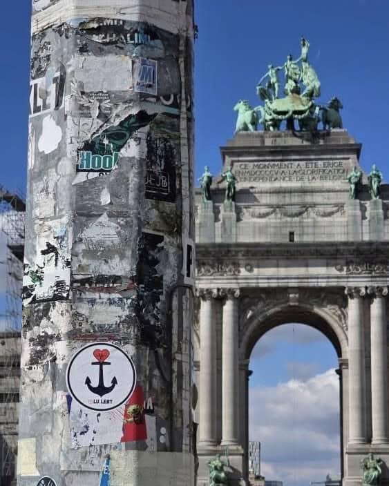 Ein Lu.lebt! Sticker wird vor einer Sehenswürdigkeit in die Kamera gehalten