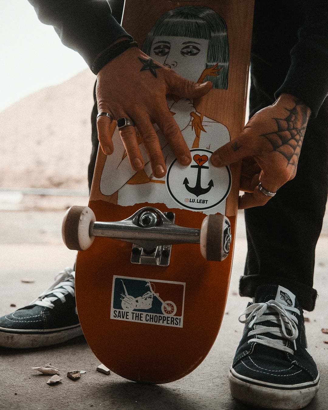 Mann klebt Sticker Lu.lebt auf ein Skateboard