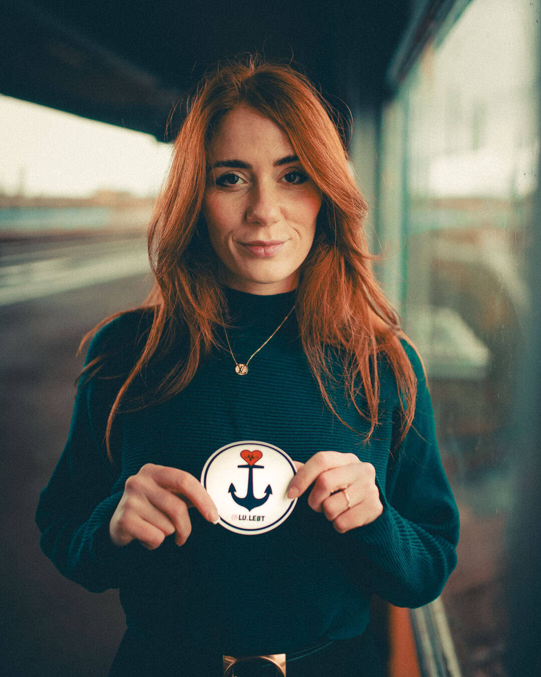 Gizem hält einen Lu.lebt! Sticker in die Kamara