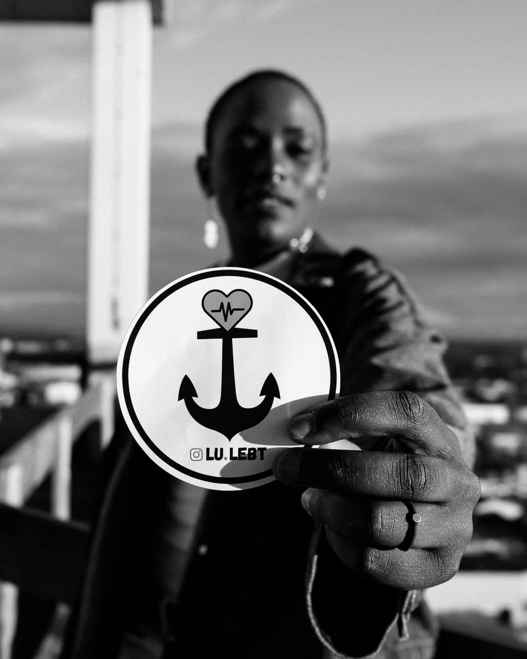 Model hält einen Lu.lebt! Sticker in die Kamara