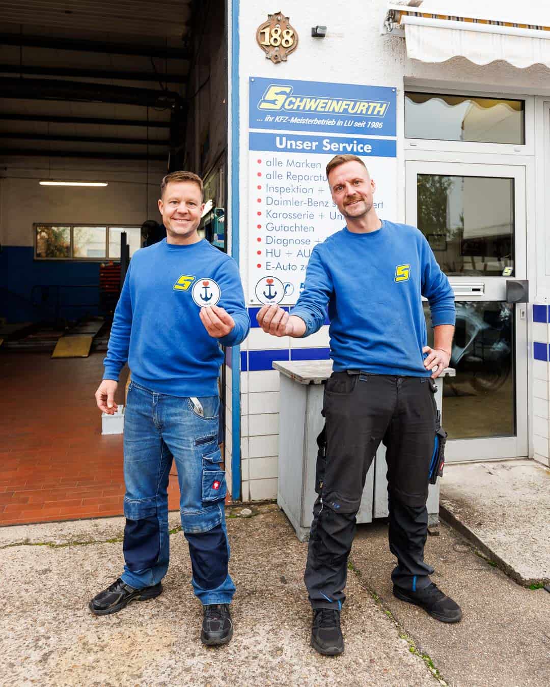Daniel und Markus Schweinfurth halten einen Lu.lebt! Sticker in die Kamera