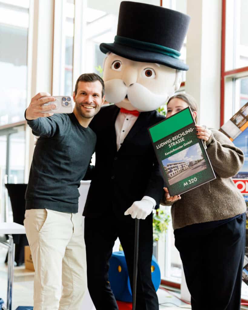 Ein Mitarbeiter von Kanzleibooster macht ein Selfie mit der großen Monopoly Figur