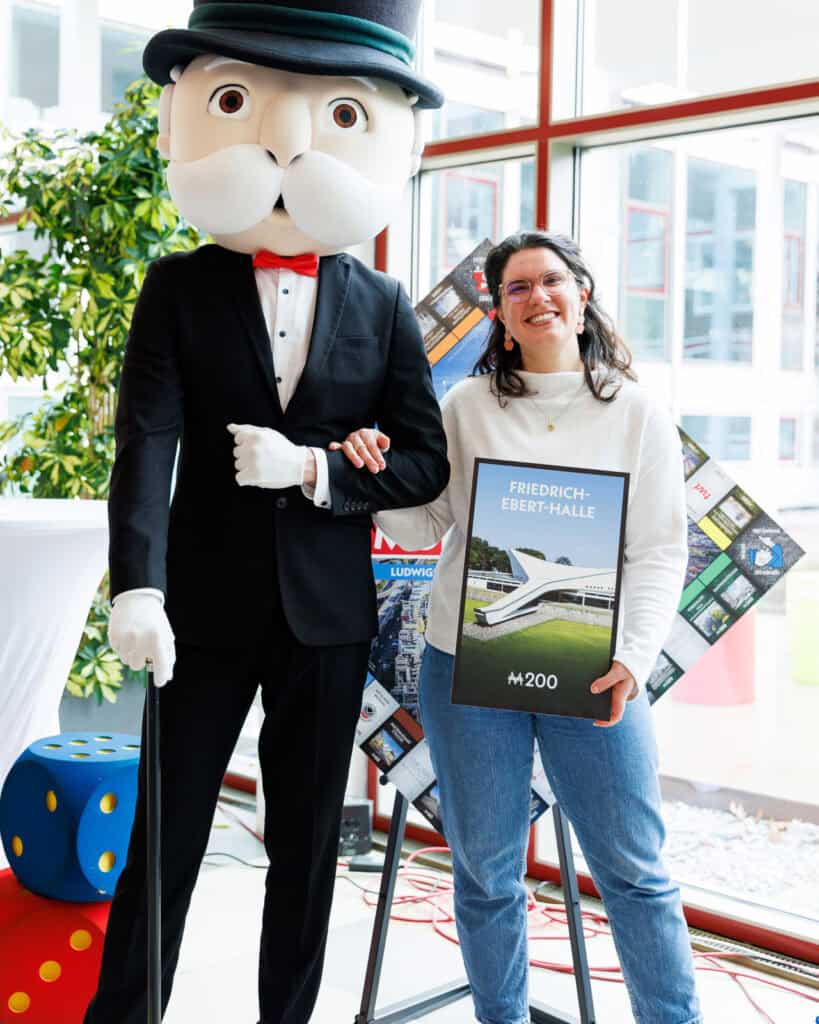 Eine Mitarbeiterin der LUKOM präsentiert das Straßenschild der Eberthalle