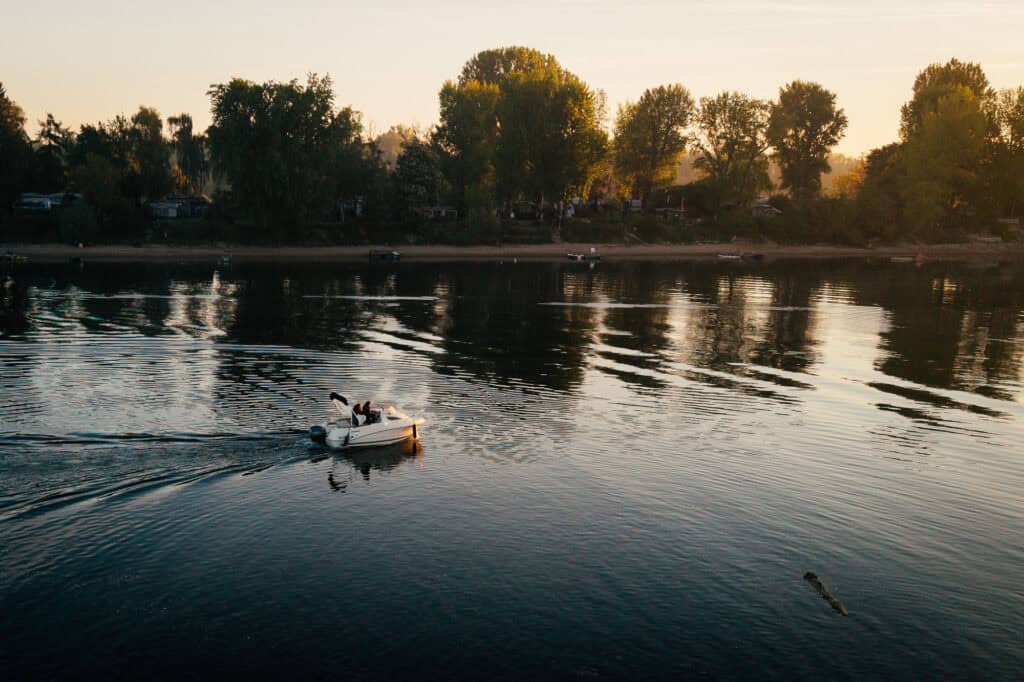 Das Schulungsboot "Kleene" fährt morgens auf dem Kiefweiher in Ludwigshafen, seichte Wellen auf dem Wasser