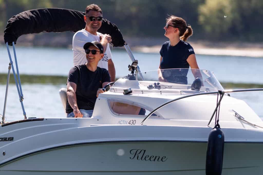 Dominique und 2 männliche Schüler lachen auf dem Boot und haben Spaß am manövrieren