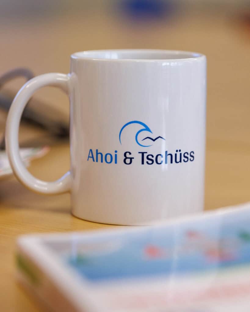 Tasse mit der Aufschrift "Ahoi und Tschüss" und dem Firmenlogo der Bootsschule
